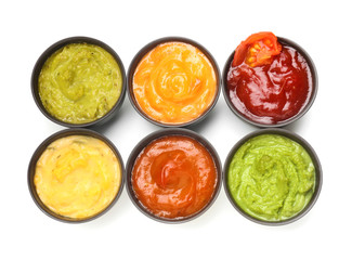 Different tasty sauces in bowls on white background