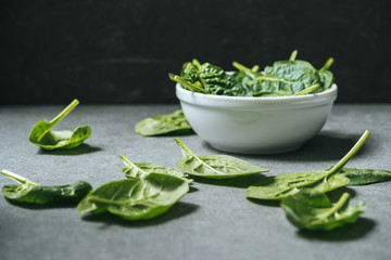 Flat lay of organic spinach leaves near white bowl with spinach