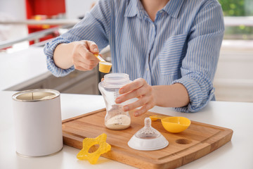 Woman preparing baby formula at table