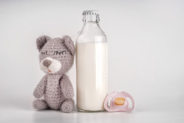 Bottle of milk with baby toy and pacifier white background