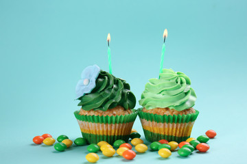 Tasty birthday cupcakes with burning candles on color background