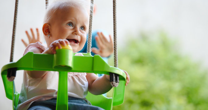 Beautiful Baby swinging outdoor with caring faimly