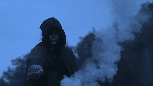 Gothic girl carring Carve pumpkin and smoke pipe. Walking through the smoke at dark scene.