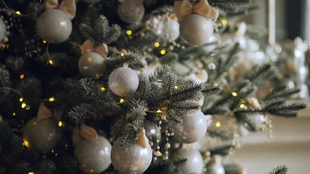 Close-up shot of decorated green Christmas tree branch with beautiful shiny balls and lights pretty decorations. New Year Day and interior concept.
