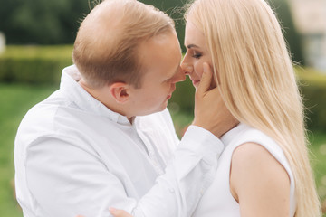 Fototapeta premium Partrait of man and woman wearing white clothes. Green background. Blond hair woman smile. Lovestory