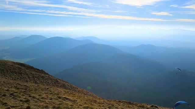 Unidentified people paragliding over a beautiful volcanic landscape in Central Massif in France.