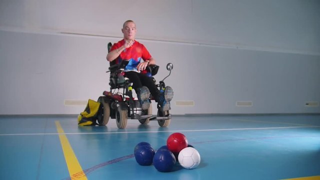 A disabled man in a wheelchair. Throwing a blue little ball. Boccia.