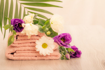Obraz na płótnie Canvas Stack of soft terry towels with flowers on wooden boards