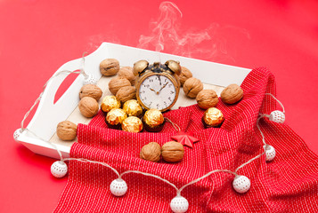 Wooden tray on a red background with nuts lying on a red napkin. The scenery for the New Year's Eve. romantic setting with a candle.. Candle Smoke