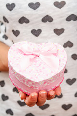 Woman holding a gift box tied with red ribbon in the hand.