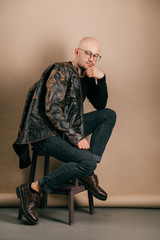 Lifestyle portrait of fashionable stylish bald man in glasses. Awesome man wearing biker leather...