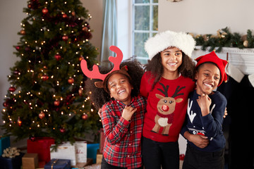 Portrait Of Children Wearing Festive Jumpers And Hats Celebrating Christmas At Home Together