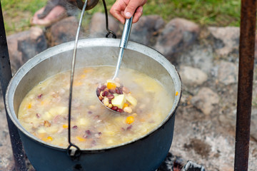 Cooking food in a pot on campfire. Summer camping concept.