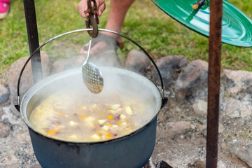 Cooking food in a pot on campfire. Summer camping concept.