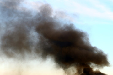 heavy smoke pillar on the blue sky background.