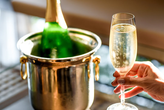 Girl hand with manicure hold champagne glasses on a beautiful summer terrace. sparkling champagne glasses