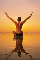 Silhouette of a young and fit woman on the beach at sunset