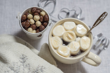 A cup of cocoa with marshmallows and corn balls on a white backg