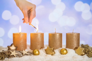 Two advent candles in snow lit by match in hand - 233533774