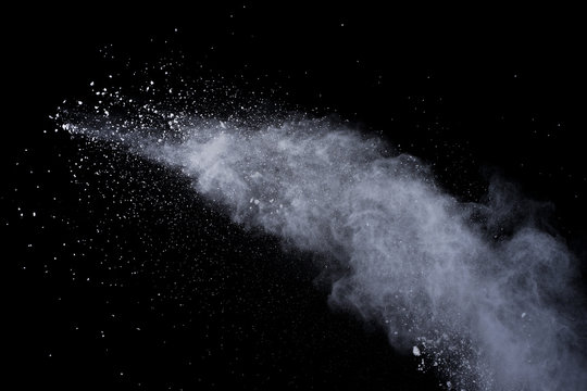 White powder explosion on black background. Dust splatted isolated. Paint Holi.