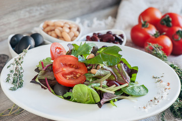 Salad for the correction of the weight of the leaves of Lollo Rosso lettuce, watercress salad and other green herbs with tomatoes, olives and phytacs