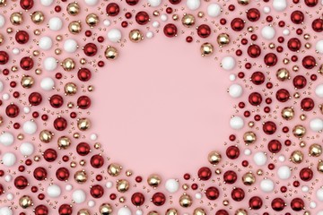 Minimal christmas background composition. Scattered red, gold, white decoration balls and stars on pastel pink background with a circle note space. 3D rendering.