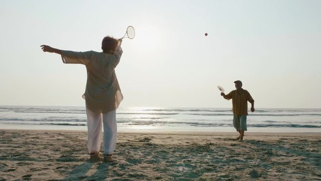 Active senior couple playing tai chi ballon ball at the beach.