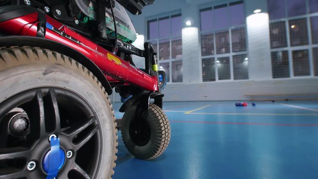 A disabled man in a wheelchair playing boccia. Throwing the ball. Hand in the frame
