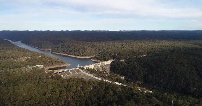 Massive concrete warragamba dam on Warragamba river in Sydney West surrounded by clean evergreen gum-tree woods.
