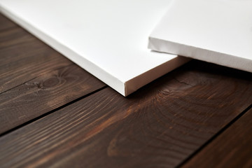 Two white blank canvases on brown wooden background. Mockup