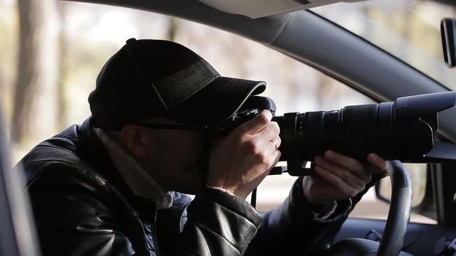 Spy, paparazzi or detective in the car, shooting on camera.