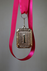 Medal for first place on a bright pink ribbon symbolizing success