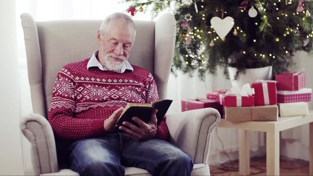 A senior man reading bible at home at Christmas time.