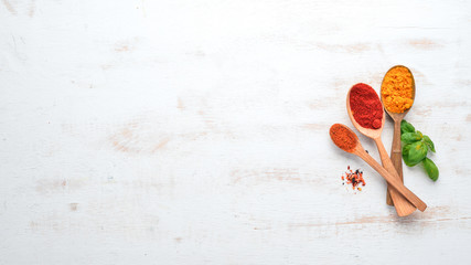 A set of Spices and herbs on a white wooden table. Basil, pepper, saffron, spices. Indian...