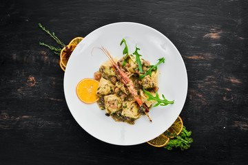 Ravioli with shrimp and seafood. Italian cuisine. Dumplings. In a plate on a wooden background. Top view. Free copy space.