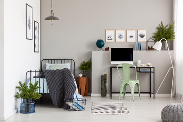 Bright grey bedroom interior with workspace with desk and computer, real photo with copy space on...