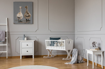 White wooden cradle with emerald pillow and toys in the corner of stylish scandinavian baby bedroom...
