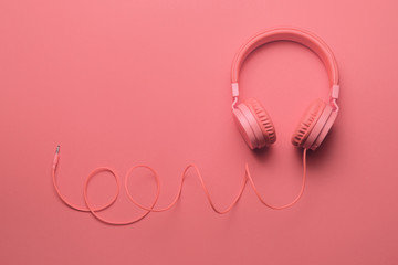 Pink headphones on pink background. Music concept