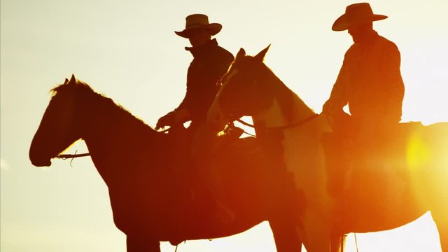 Silhouette of cowboy riders in forest wilderness area of Canada at sunrise