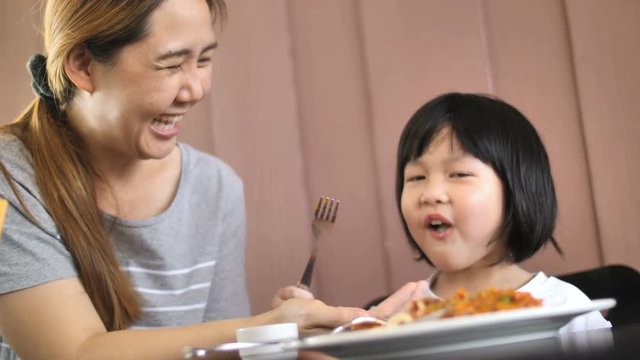 4K : Happy Asian child eating delicious spaghetti with her mother