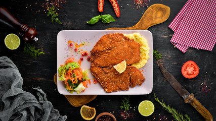 Chicken schnitzel with mashed potatoes on a plate. On a wooden background. Top view. Free space for...