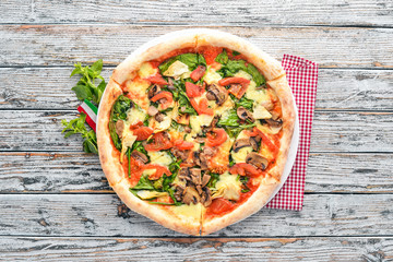 Pizza with artichokes, spinach and mushrooms. On a wooden background. Top view. Free copy space.