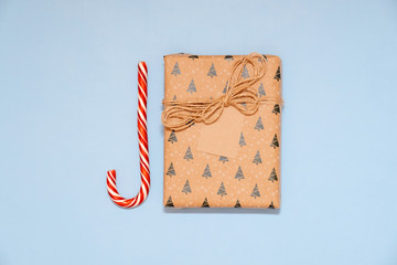 Christmas candy cane and gift box with craft retro label on blue background. Flat lay, top view, overhead.