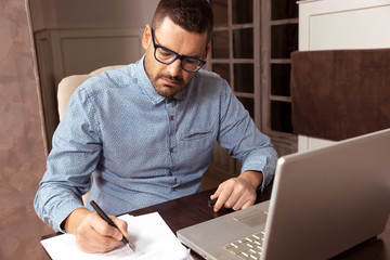 Hombre de negocios escribiendo con su ordenador personal en cafetería - obrazy, fototapety, plakaty