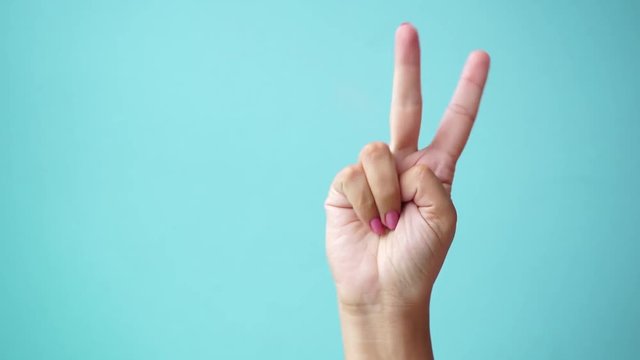 Closeup of isolated on green adult female hand counting from 0 to 5. Woman shows fist fist, then one, two, three, four, five fingers. Manicured nails painted with beautiful pink polish. Math concept.