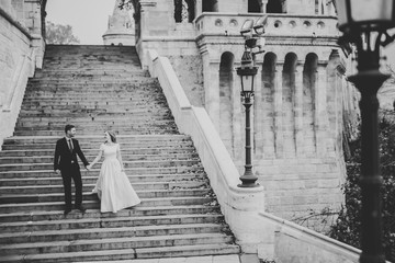 Beautiful wedding couple climbing up a gorgeous stairs holding hands and looks to each other