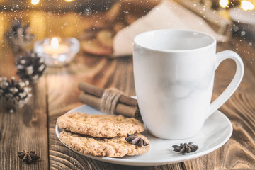 Tea mug on a plate with oatmeal cookies, cinnamon and anise seed