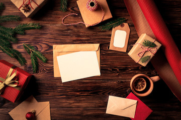 Letter to Santa Claus concept. Top view of composition with christmas gifts and decoration. Vintage toned image with blank wish list for christmason wooden background, flat lay, copy space.