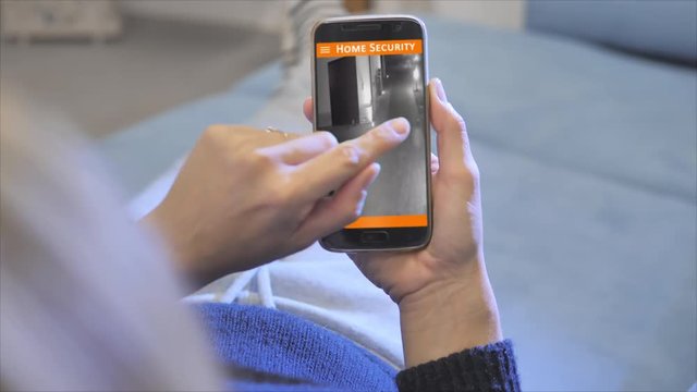 woman looking home security camera from smartphone application