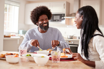 Happy black couple enjoying eating their Sunday dinner together at home, close up
